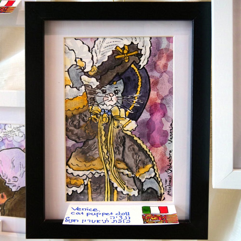 Watercolour painting, vertical, with ink lines, of a antropomorphic cat figurine in a fantasy renaissance-ish theatre costume. The cat wears a big hat with feathers, and holds a piece of cloth in right paw. The background is painted in circles of different purple-ish colours.
The painting is in black frame on white background, signed in English and Hebrew, with flags of Italy and Venice drawn on the side of the hand-written plaque. Behind, around the cloth on which the painting is mounted are a few more paintings peeking.